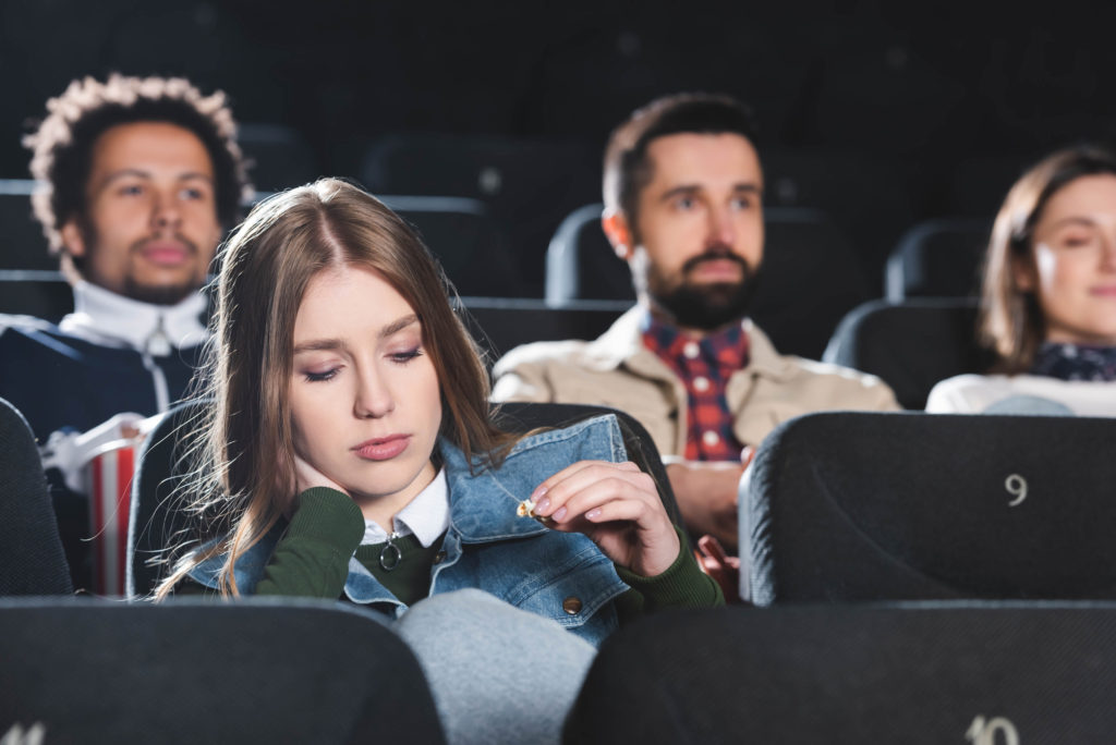 woman in movie theater looking bored
