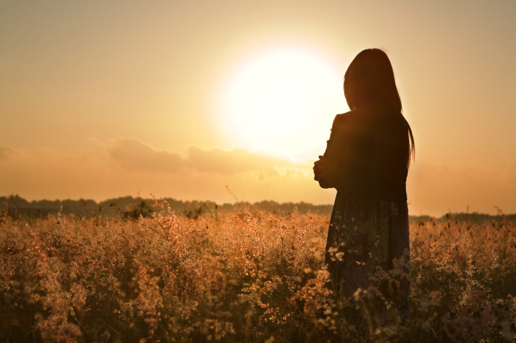 girl standing in the sun in a field
