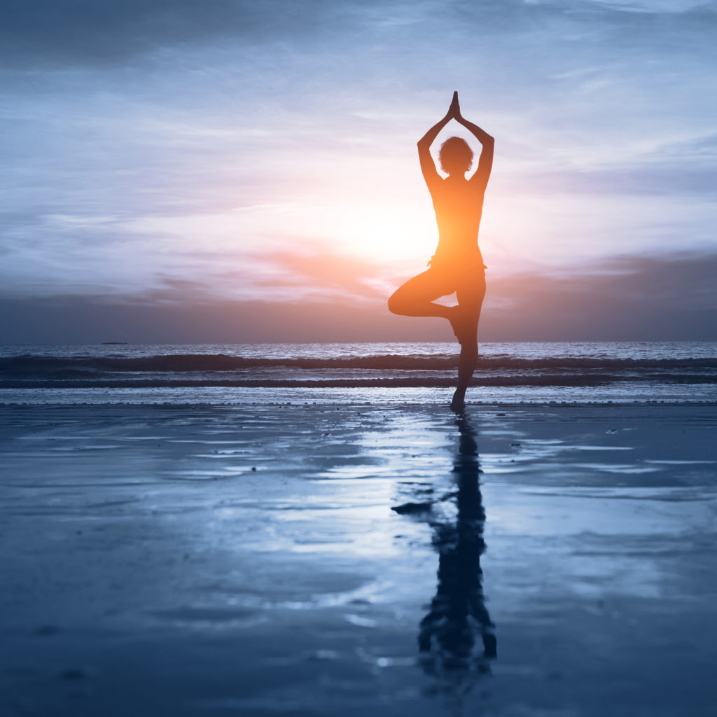 woman doing yoga in the water during sunset