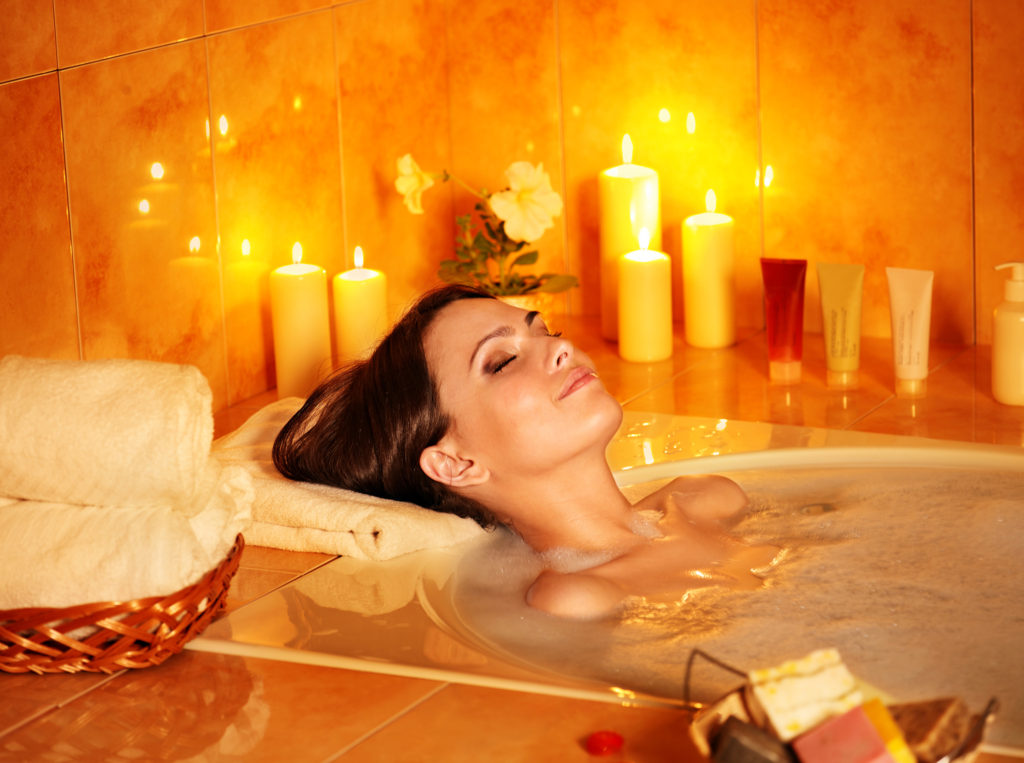 woman in bath tub with candles