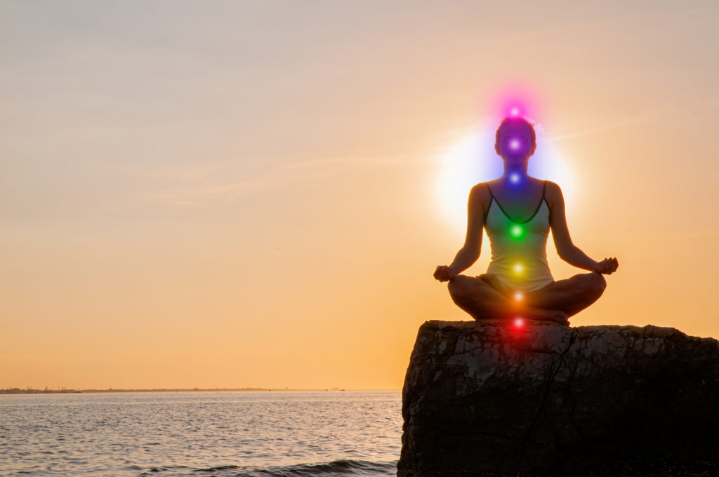 woman doing a chakra meditation and sunrise